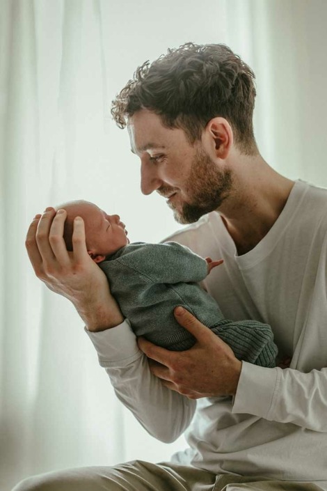 Vater-Sohn-Moment, Papa schaut Sohn an, Vater hält Sohn im Arm